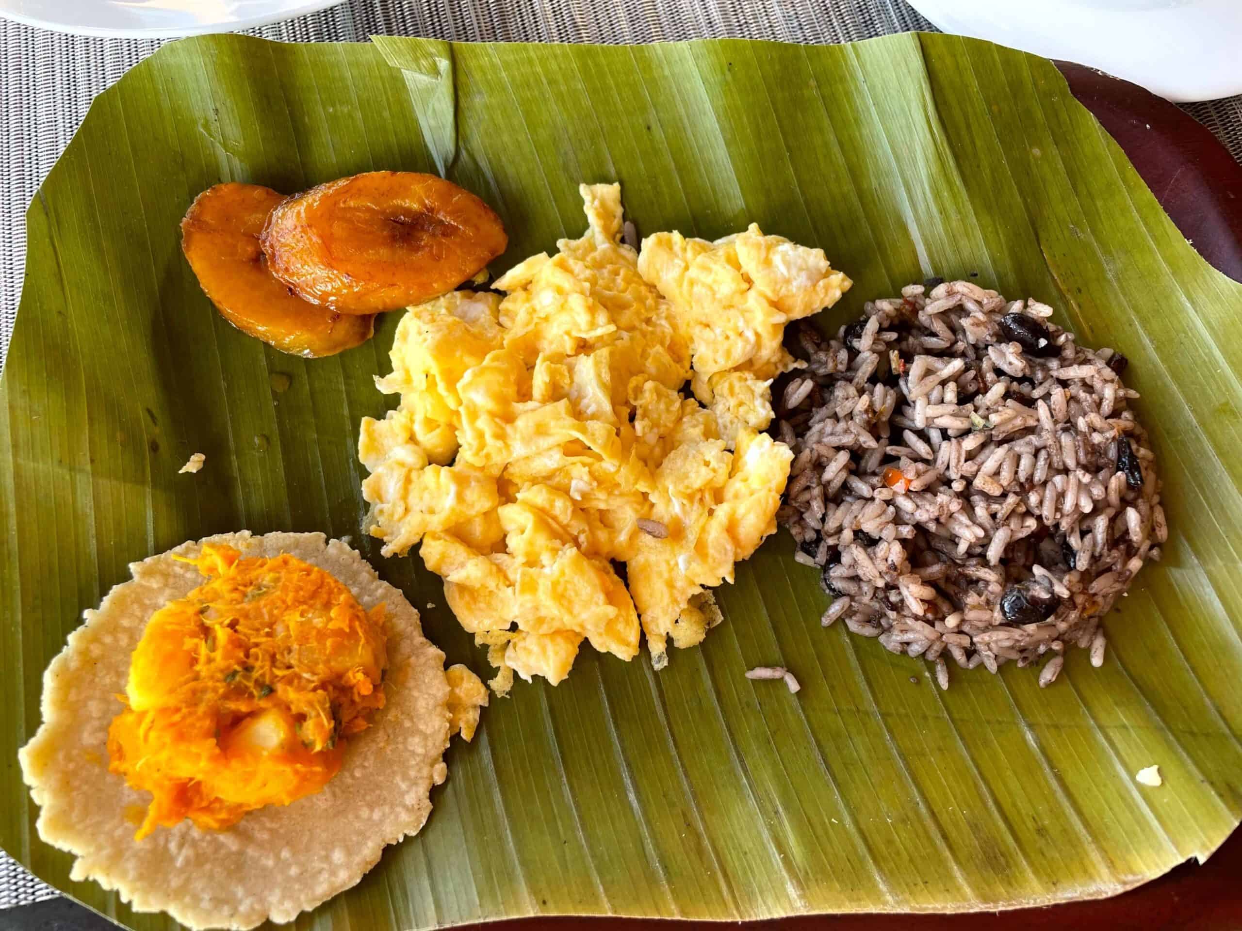 Typical Costa Rican breakfast including Gallo Pinto, scrambled eggs, and fried plantains served on a banana leaf