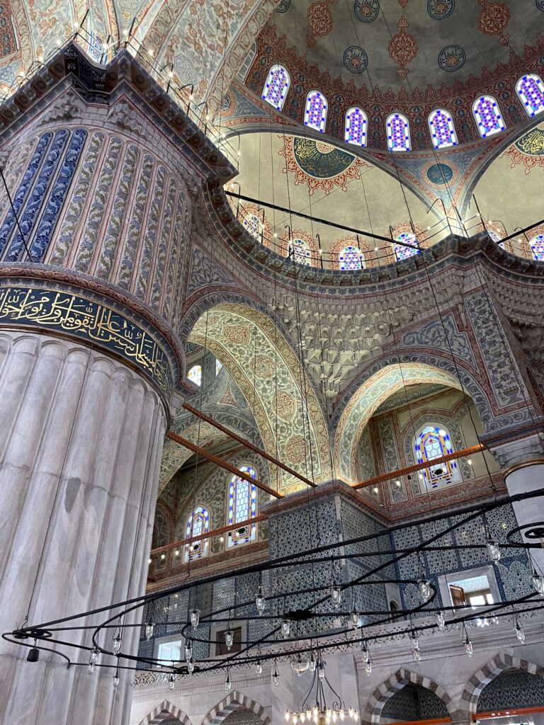 The columns and upper walls of the Blue Mosque covered in tiles and painted patterns.