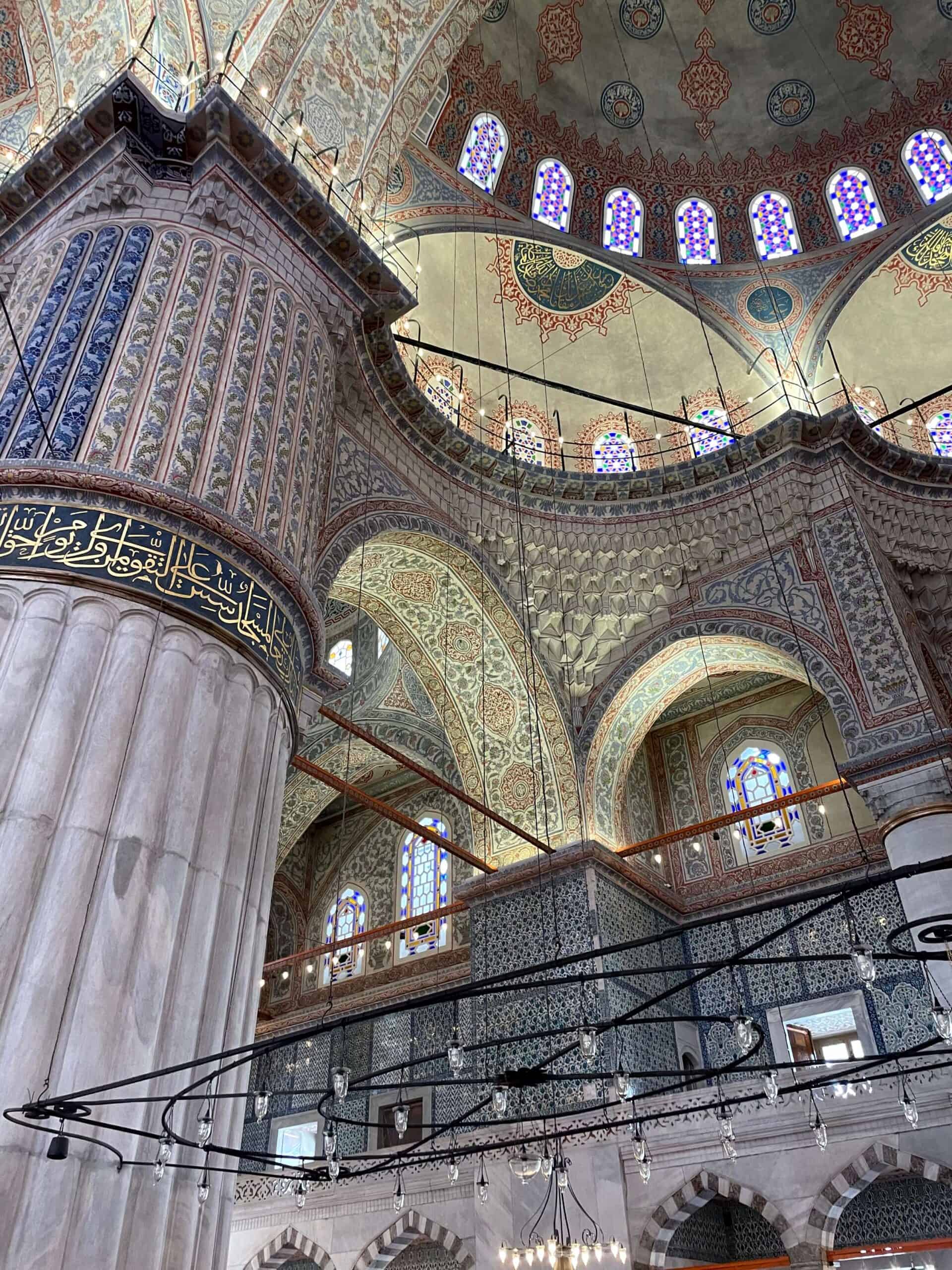 The columns and upper walls of the Blue Mosque covered in tiles and painted patterns.