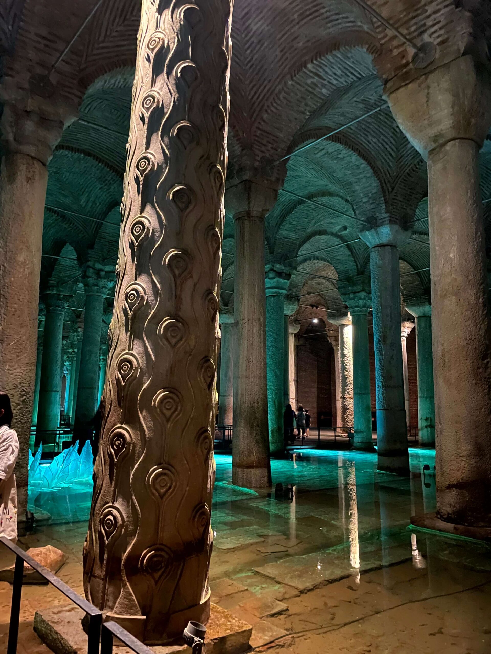 The inside of the Basilica Cistern with marble columns rising from the shallow water and a sculpture in the background.