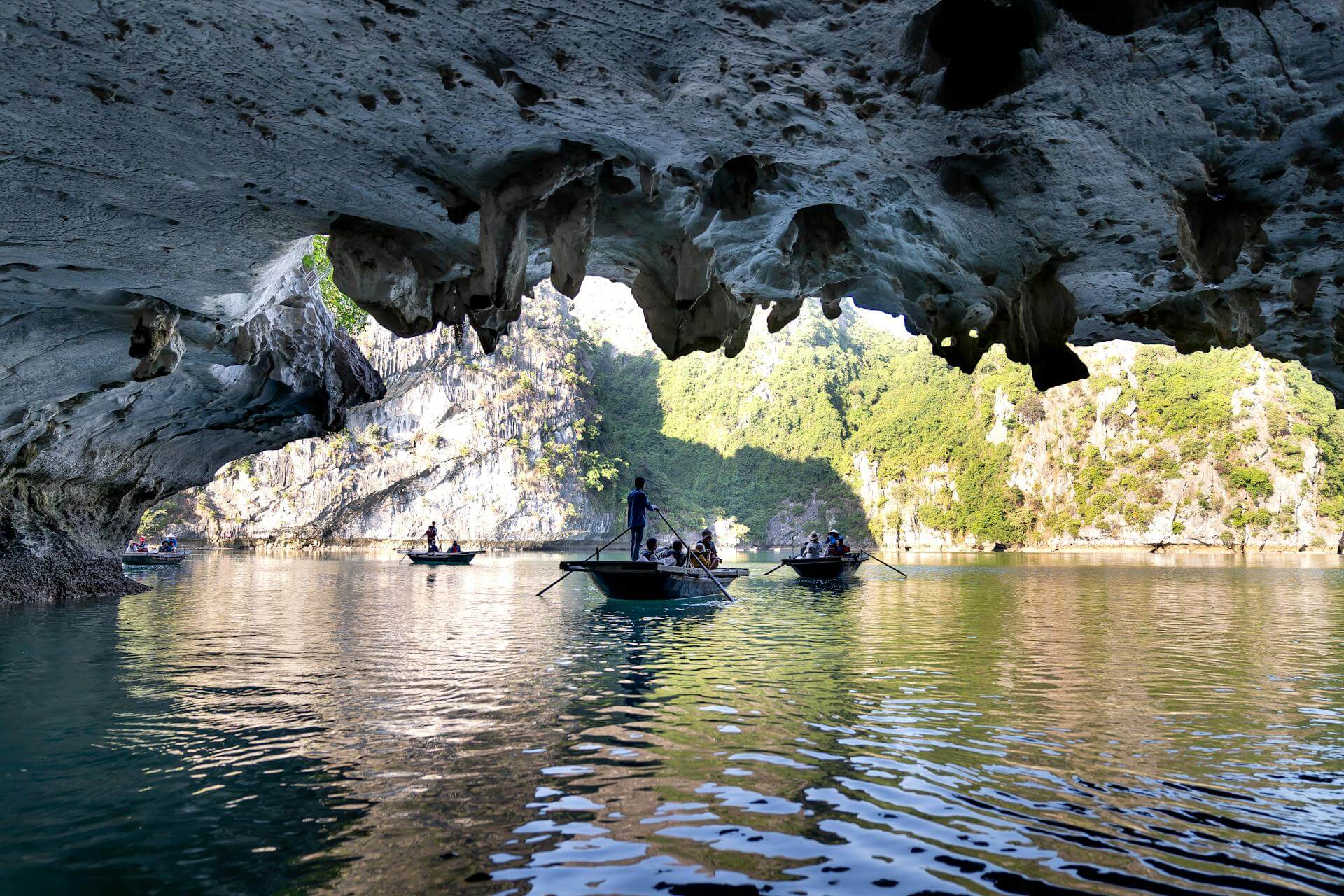 Guides rowing small bamboo boats through the Dark and Light Cave in Lan Ha Bay