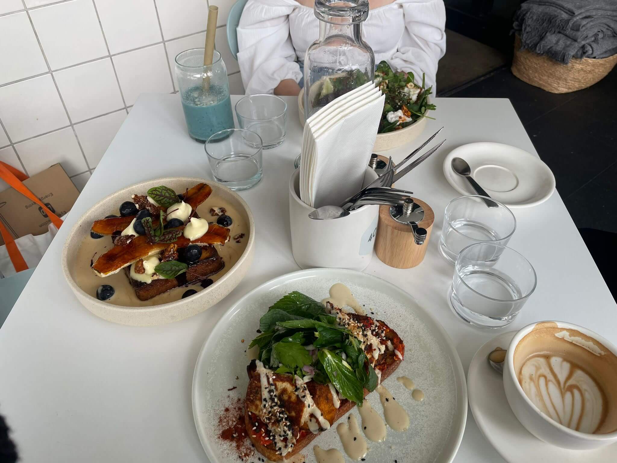 Brunch spread on a café table with toast, eggs, greens, and coffee, showing a relaxed dining experience with friends.