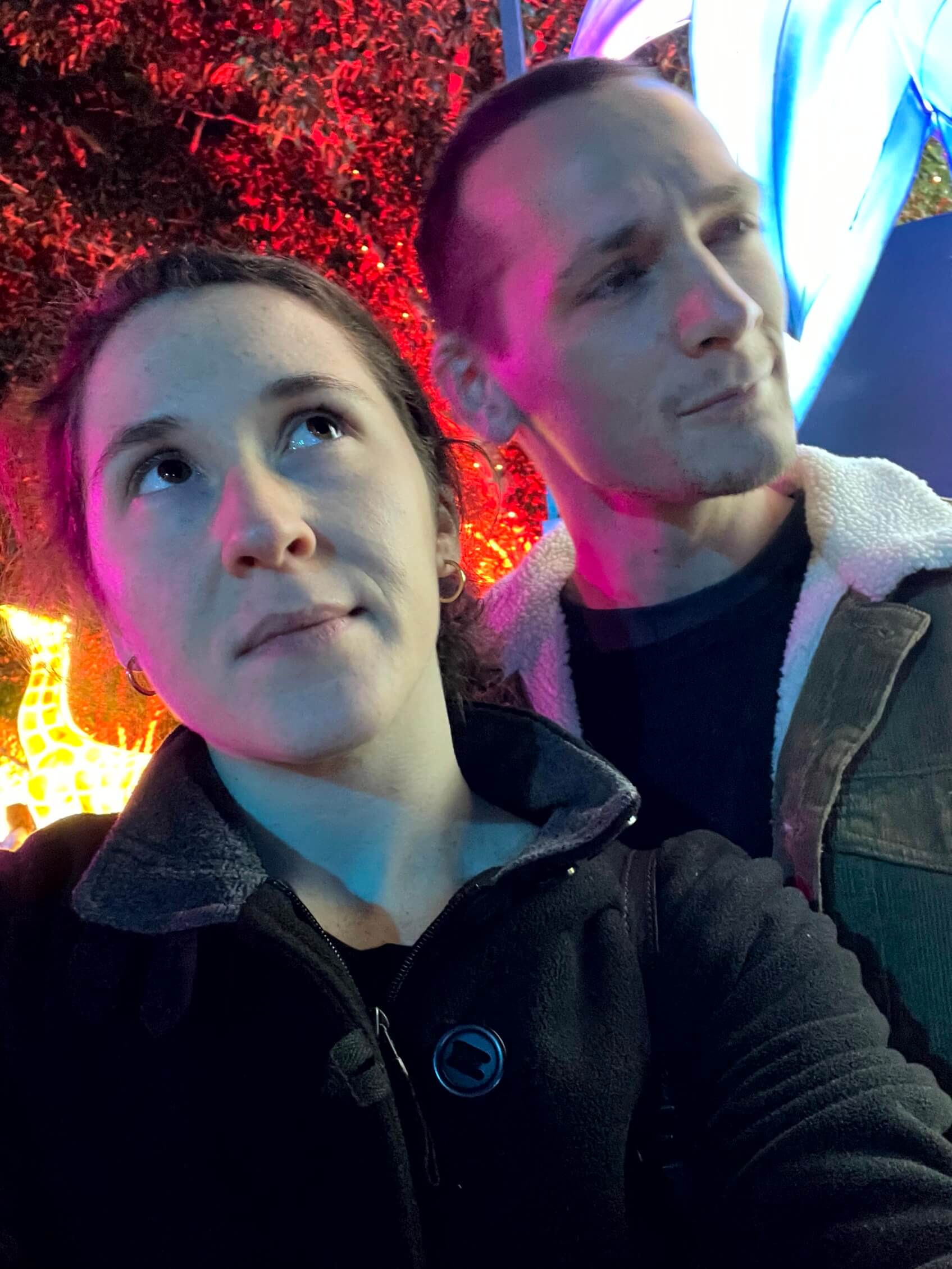 Rebecca and her partner Patrick surrounded by colourful light displays at GLOW Sydney Zoo.