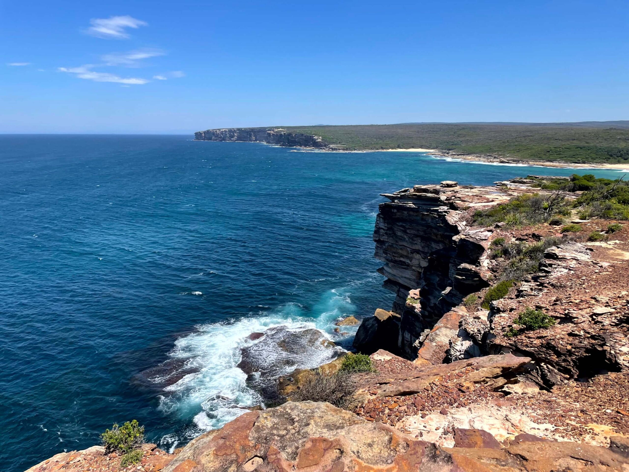 Rocky coastal cliffs along the Coast Track in the Royal National Park overlooking deep blue ocean with waves below.