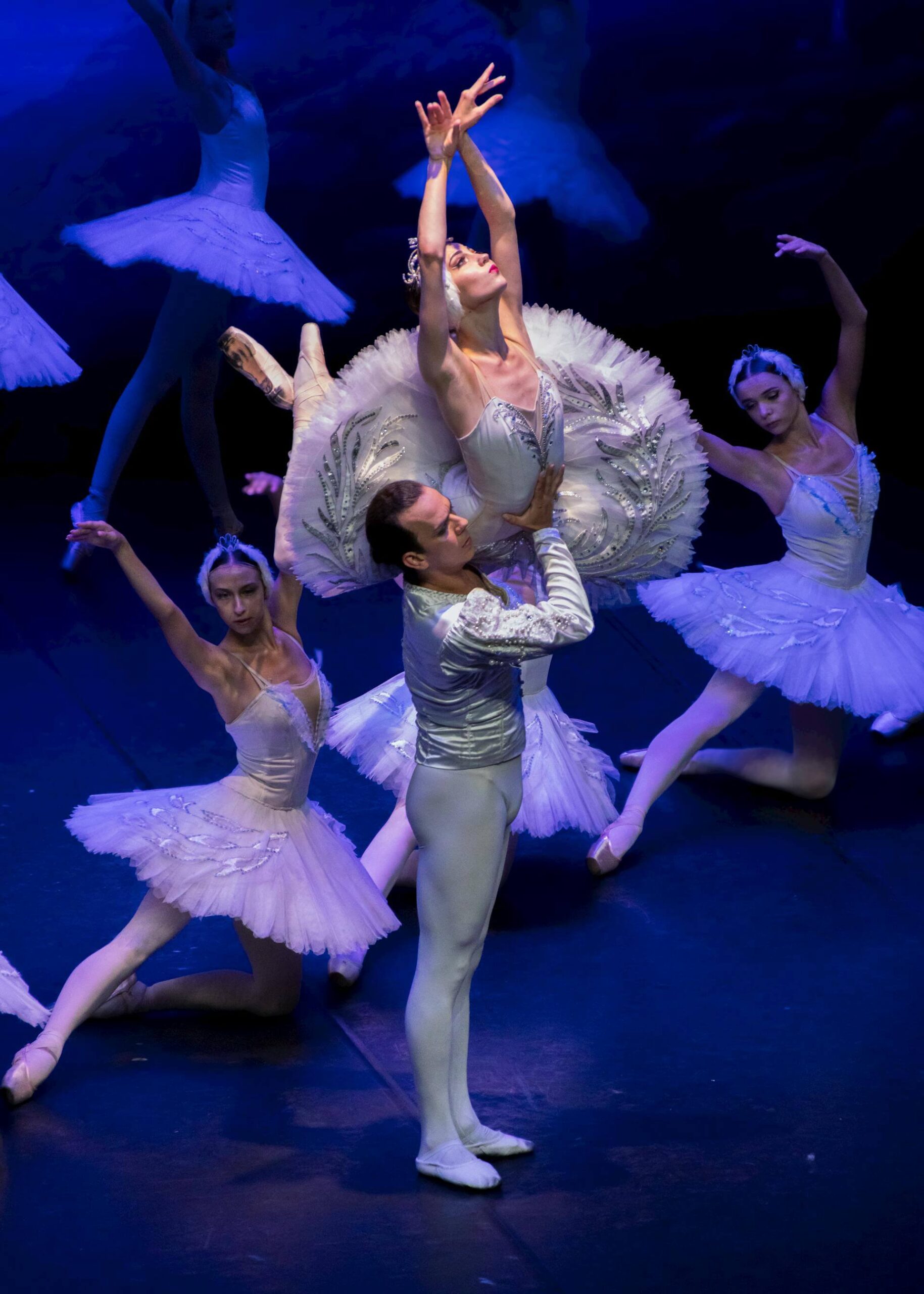 Ballet dancers performing on stage at the Sydney Opera House in white costumes under blue lighting.
