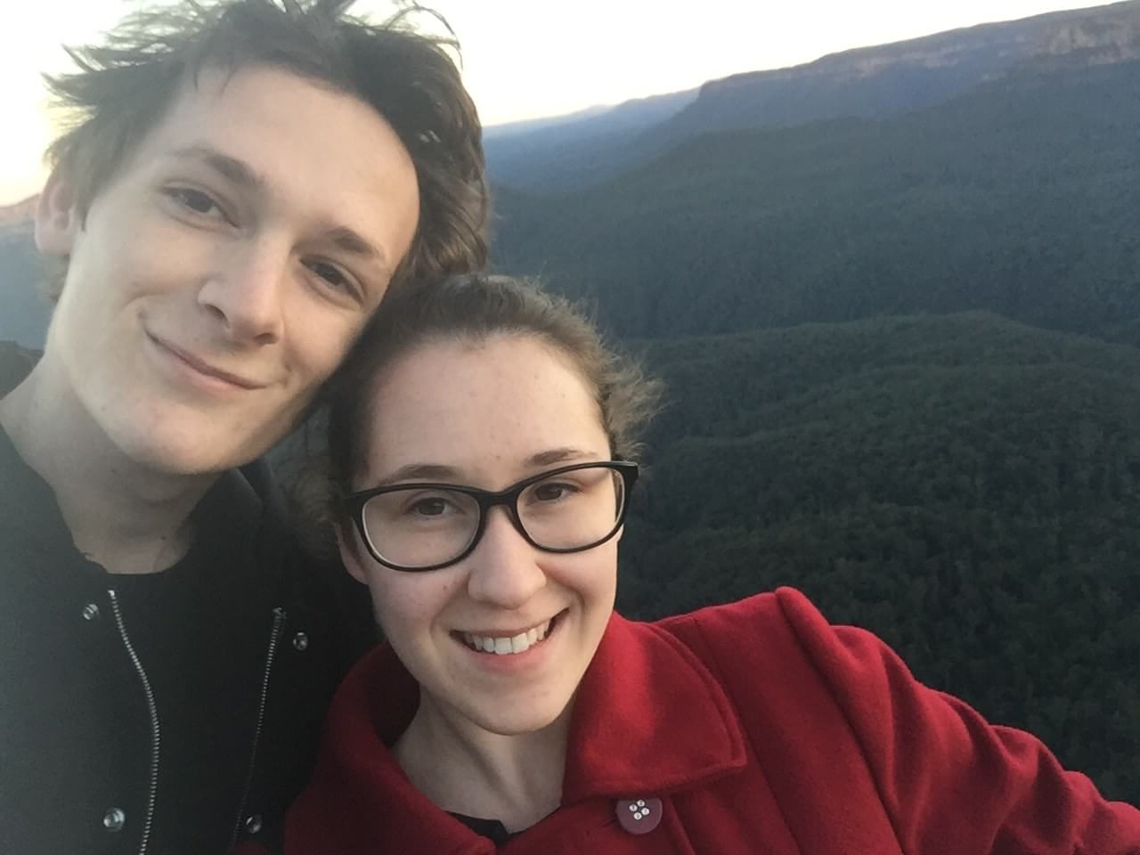 Rebecca and her partner Patrick smiling in a selfie at Echo Point Lookout in the Blue Mountains.