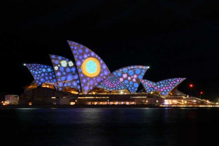 Sydney Opera House lit up with colourful Vivid Sydney projections at night.