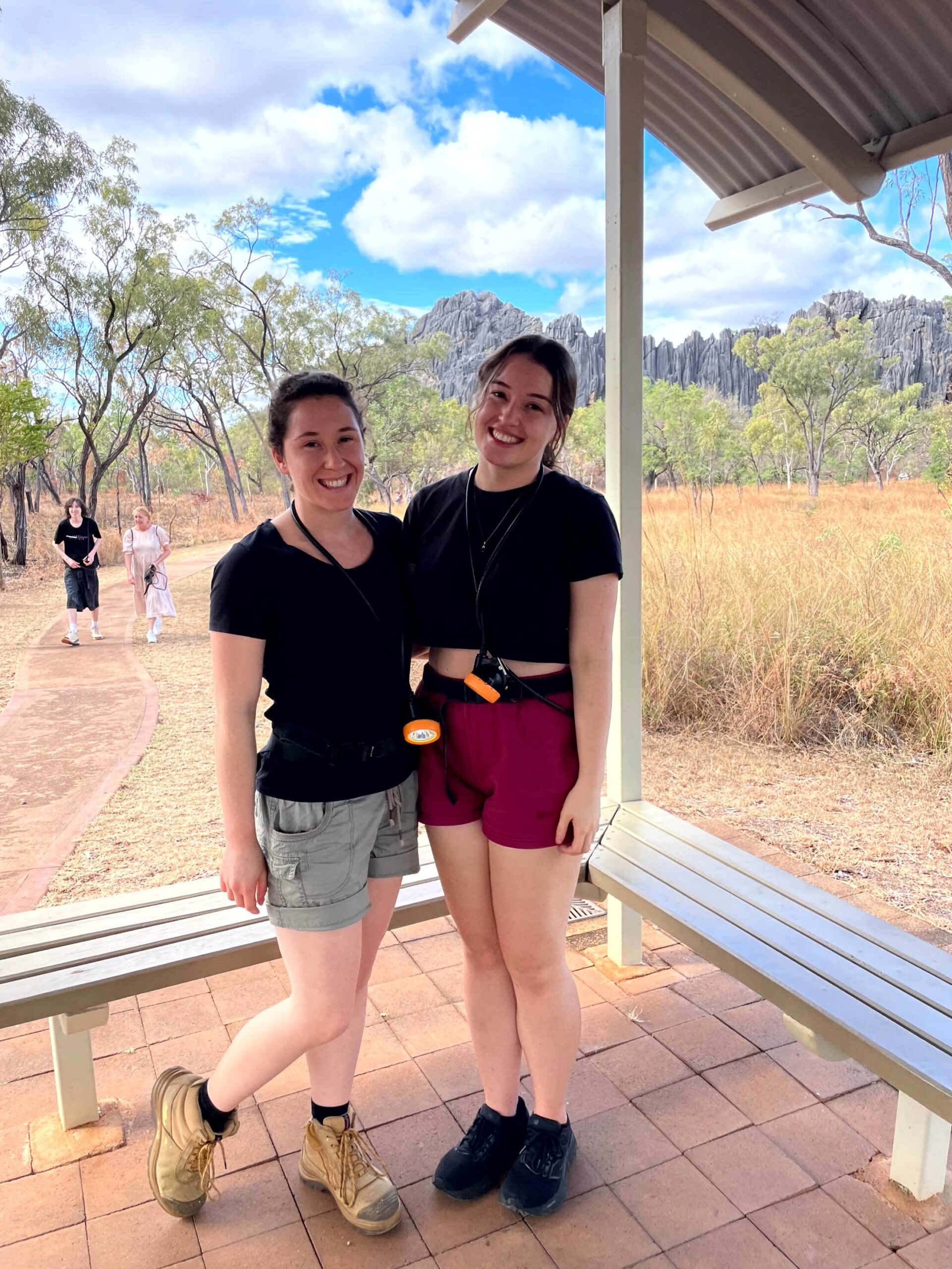 Rebecca and her sister in front of the Royal Arch Bluff with torches around their necks used for the cave tour which is one of the best things to do in Chillagoe.